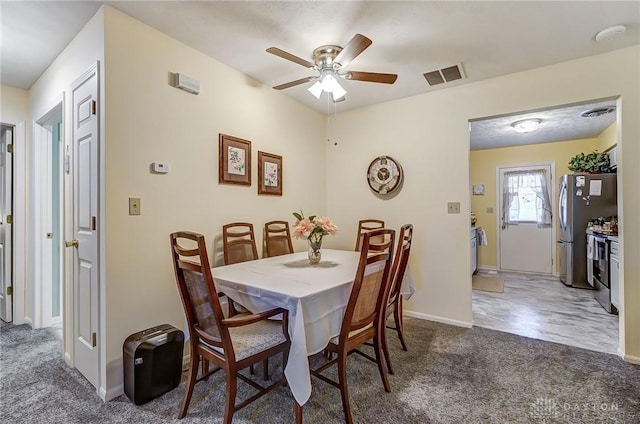 dining space featuring ceiling fan and dark colored carpet