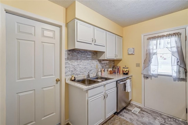 kitchen featuring dishwasher, sink, a textured ceiling, and backsplash