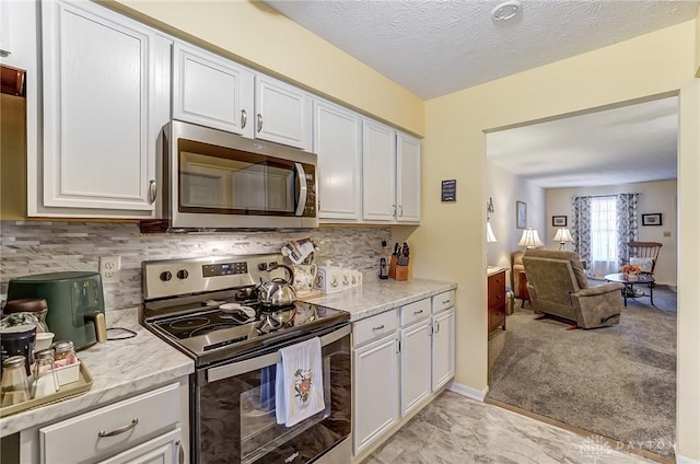 kitchen featuring white cabinets, backsplash, stainless steel appliances, light carpet, and a textured ceiling