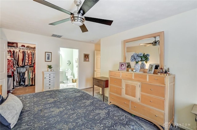 bedroom with a spacious closet, connected bathroom, ceiling fan, and a closet