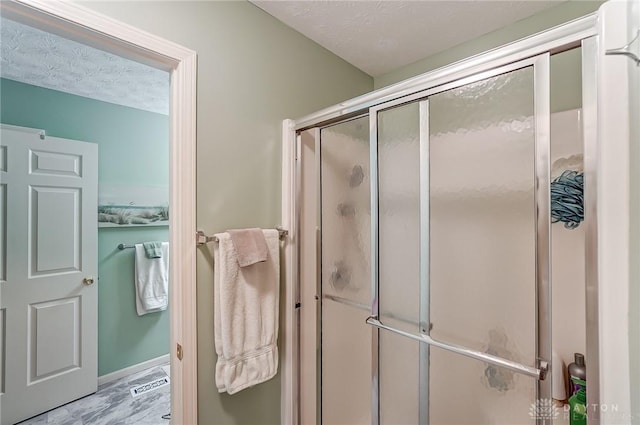 bathroom featuring a textured ceiling and walk in shower