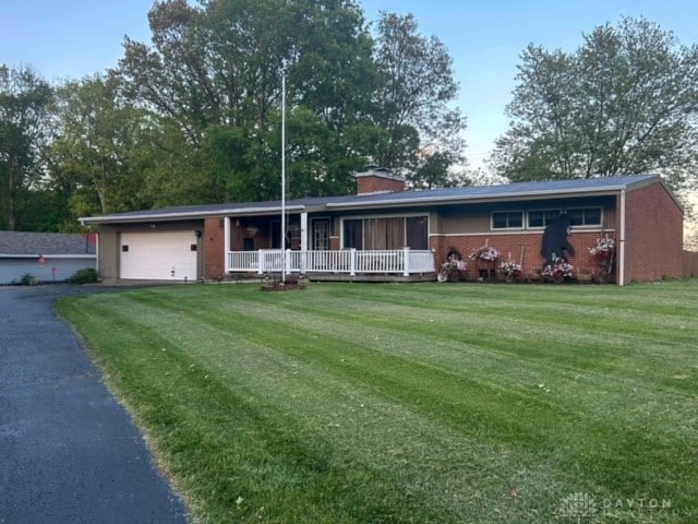 single story home with a garage, a front yard, and a porch