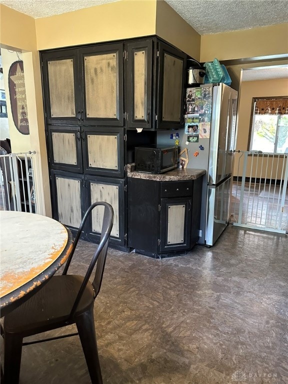 kitchen with stainless steel fridge and a textured ceiling