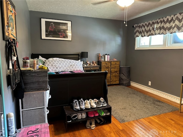 bedroom featuring hardwood / wood-style floors, ceiling fan, and a textured ceiling