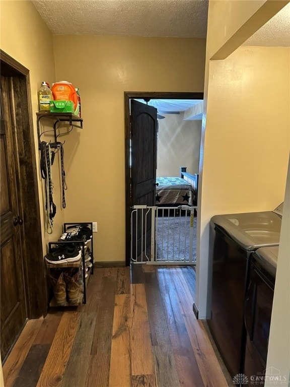 washroom with hardwood / wood-style floors, washing machine and dryer, and a textured ceiling