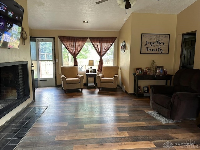 living room with dark wood-type flooring, a textured ceiling, and ceiling fan