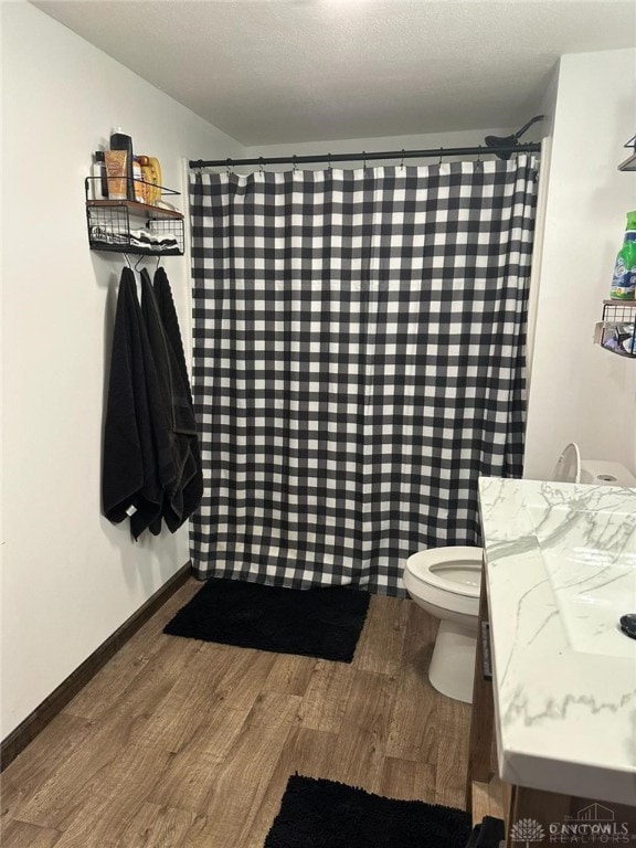 bathroom with toilet, vanity, hardwood / wood-style floors, and a textured ceiling