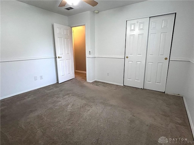 unfurnished bedroom with ceiling fan, dark carpet, and a closet