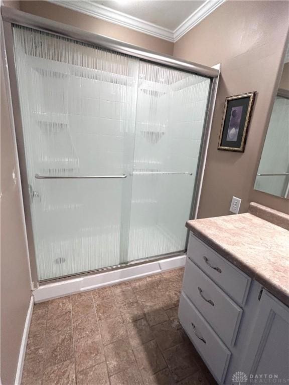 bathroom featuring a shower with door, vanity, and ornamental molding