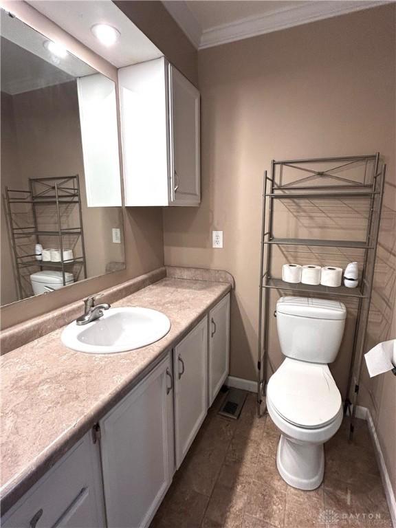 bathroom with vanity, toilet, and ornamental molding