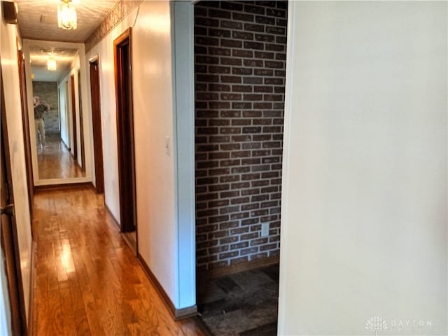 hall featuring wood-type flooring and brick wall