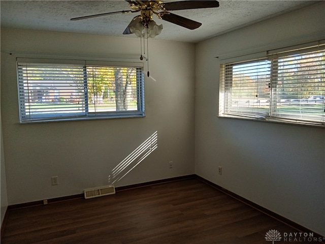 empty room with ceiling fan, dark hardwood / wood-style floors, and a textured ceiling