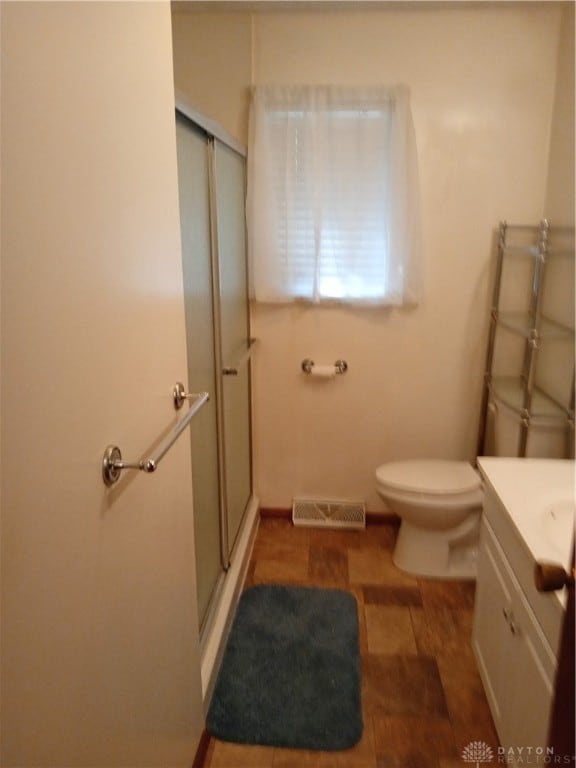 bathroom with vanity, toilet, hardwood / wood-style flooring, and a shower with door