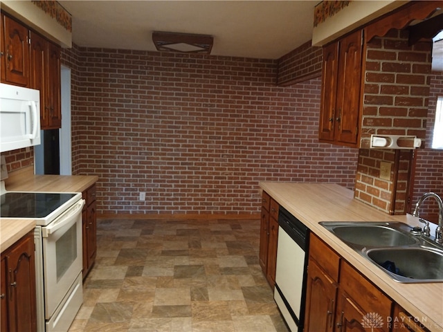 kitchen featuring brick wall, white appliances, and sink