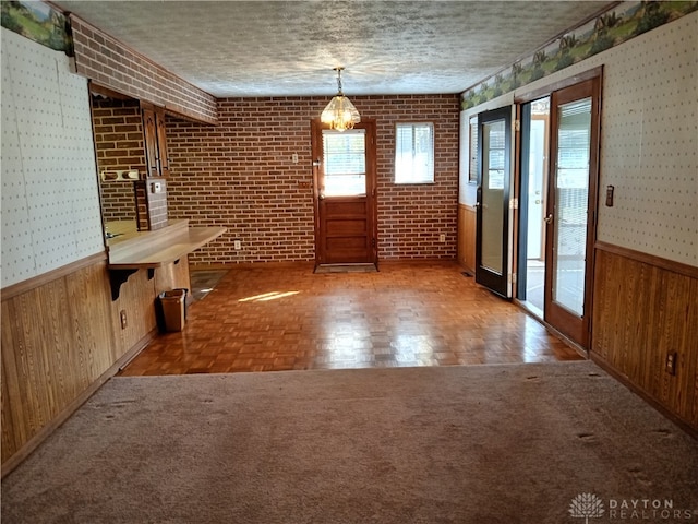 unfurnished dining area featuring parquet flooring, a textured ceiling, and wooden walls