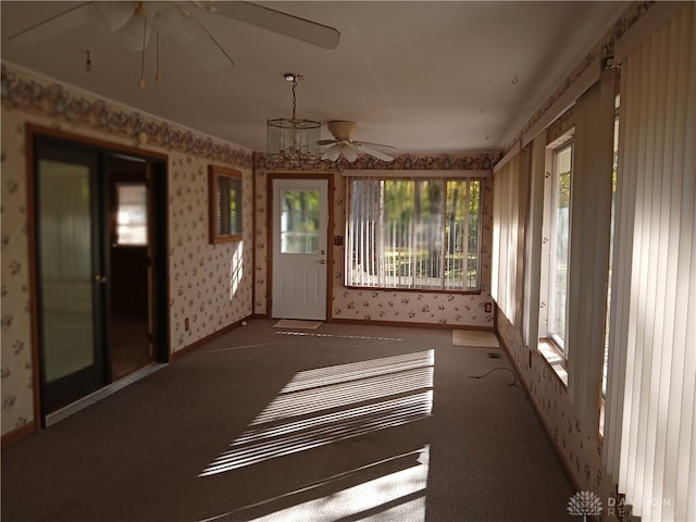 unfurnished sunroom with ceiling fan with notable chandelier