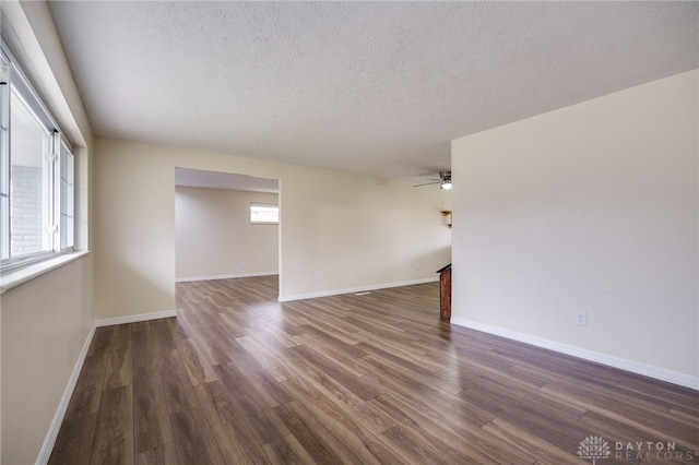 unfurnished room with a textured ceiling, ceiling fan, and dark wood-type flooring