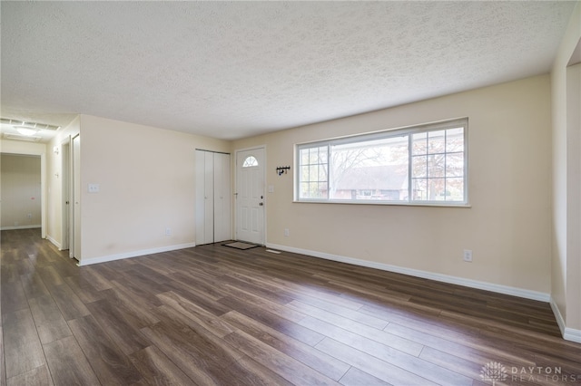 spare room featuring a textured ceiling and dark hardwood / wood-style floors