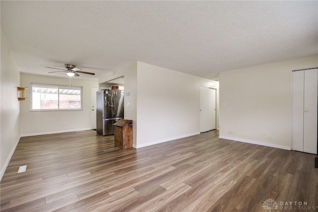 unfurnished living room with ceiling fan, a textured ceiling, and light wood-type flooring