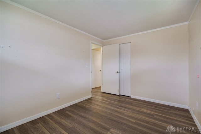 empty room featuring ornamental molding and dark wood-type flooring