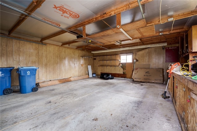 garage featuring a workshop area, a garage door opener, and wood walls