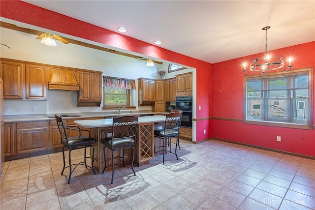 kitchen with premium range hood, a kitchen island, decorative light fixtures, an inviting chandelier, and a breakfast bar