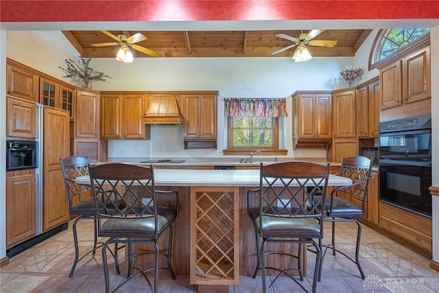 kitchen featuring black appliances, a wealth of natural light, vaulted ceiling with beams, and a breakfast bar