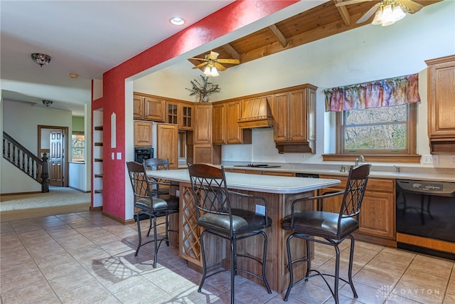 kitchen with a kitchen breakfast bar, ceiling fan, premium range hood, and black appliances