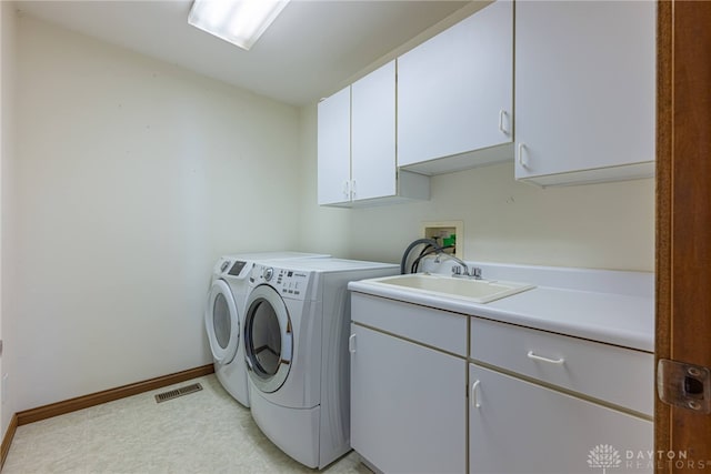 clothes washing area with cabinets, sink, and washer and dryer