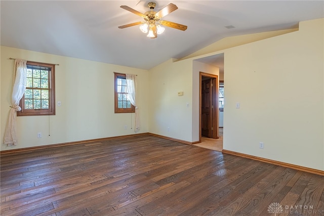 spare room with dark wood-type flooring, plenty of natural light, and vaulted ceiling