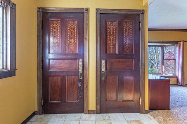 foyer with light carpet and crown molding