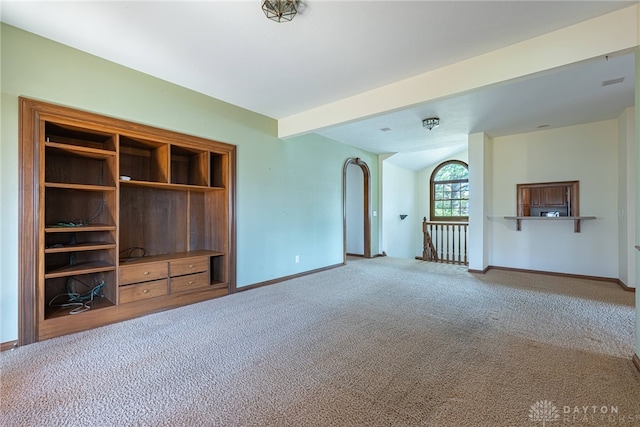 unfurnished living room featuring beam ceiling and carpet floors