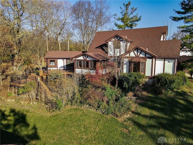 tudor house featuring a sunroom and a front lawn