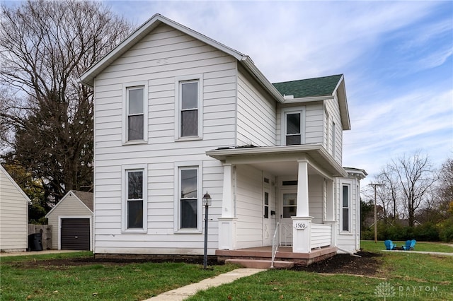 view of front facade featuring an outbuilding, covered porch, a front yard, and a garage