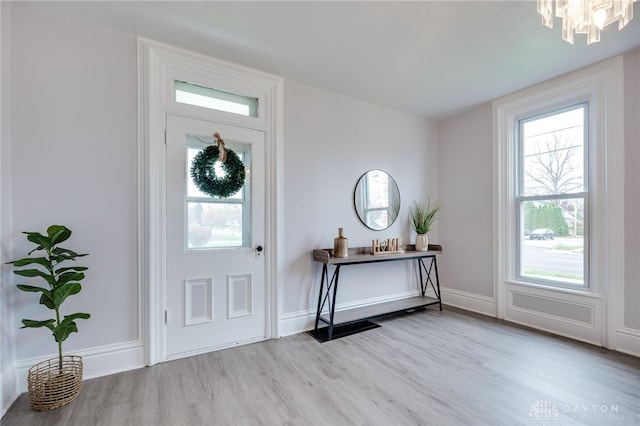 entrance foyer with light hardwood / wood-style flooring and an inviting chandelier