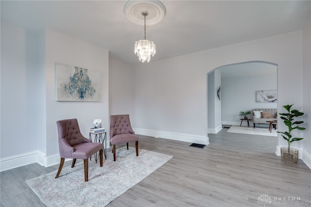 sitting room with wood-type flooring and a notable chandelier