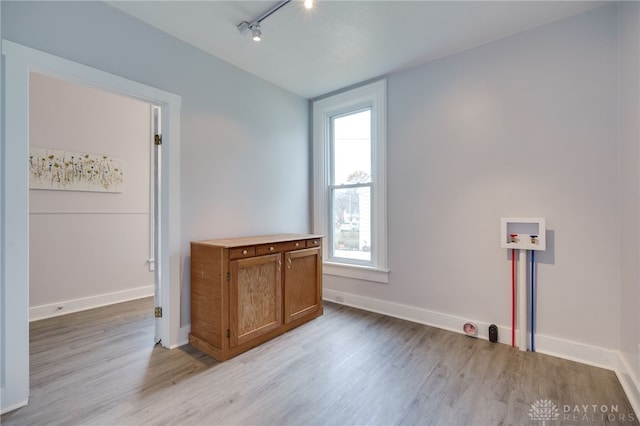 spare room featuring a healthy amount of sunlight, track lighting, and light hardwood / wood-style floors