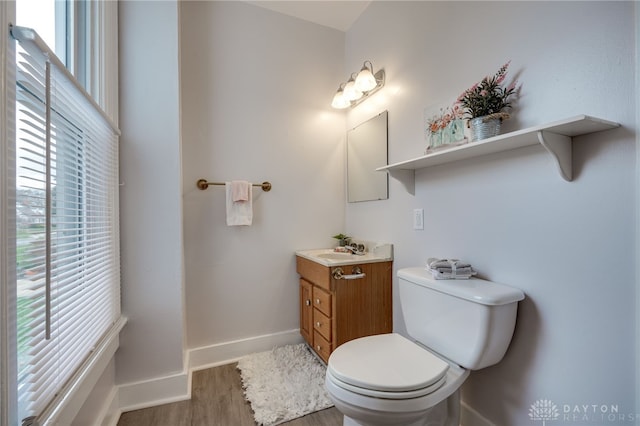 bathroom with toilet, vanity, a healthy amount of sunlight, and hardwood / wood-style flooring