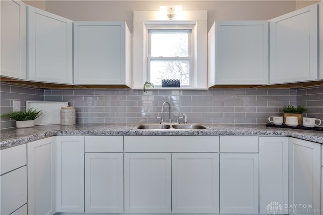 kitchen featuring white cabinets, decorative backsplash, and sink