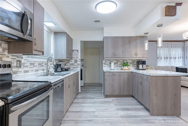 kitchen featuring a wealth of natural light, sink, decorative backsplash, and appliances with stainless steel finishes