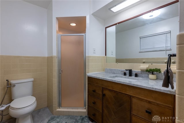 bathroom featuring toilet, vanity, tile walls, and a shower with door