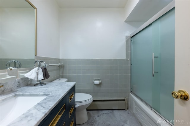 full bathroom with a baseboard radiator, toilet, tile walls, bath / shower combo with glass door, and vanity