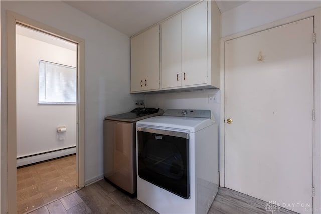 laundry area featuring cabinets, washing machine and dryer, light wood-type flooring, and a baseboard heating unit