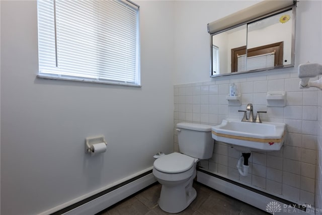 bathroom with tile walls, toilet, a baseboard heating unit, and sink