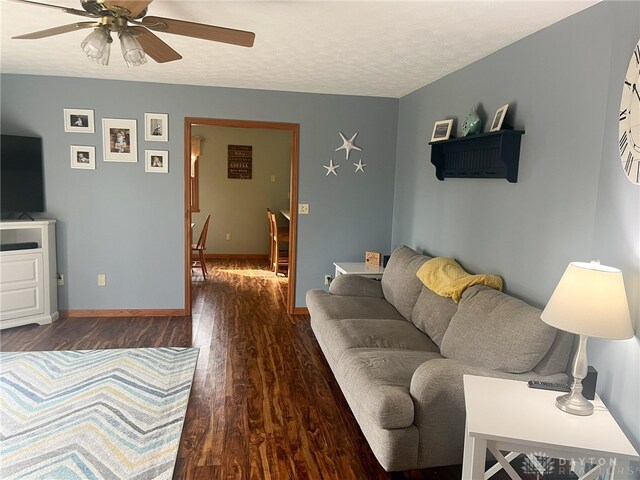 living area featuring wood finished floors, ceiling fan, baseboards, and a textured ceiling