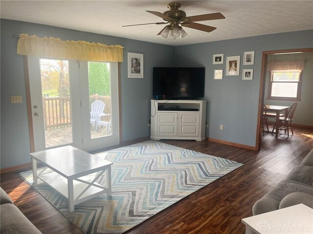 living area featuring wood finished floors, a ceiling fan, and baseboards
