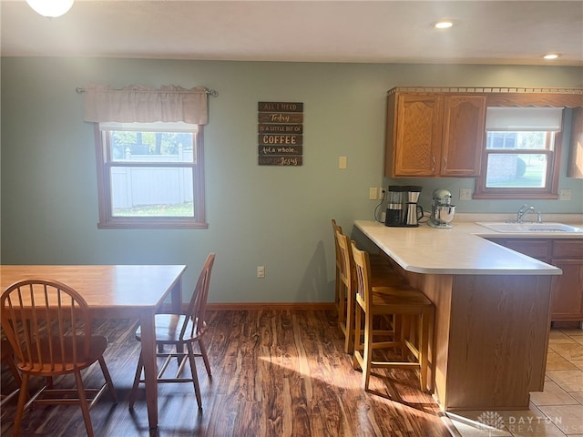 kitchen featuring light countertops, a wealth of natural light, a kitchen bar, and a sink