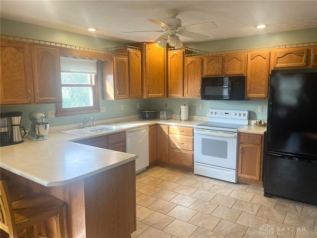 kitchen featuring a breakfast bar, light countertops, black appliances, a sink, and a peninsula