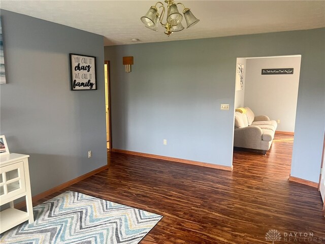 unfurnished dining area featuring baseboards, wood finished floors, and an inviting chandelier