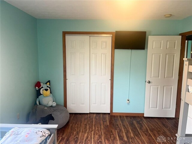 bedroom with dark wood-style floors and a closet